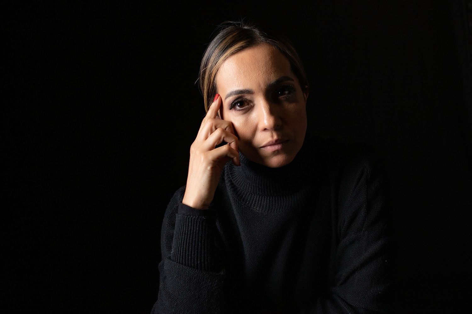 Dramatic portrait with black turtleneck against dark background showing contemplative expression.