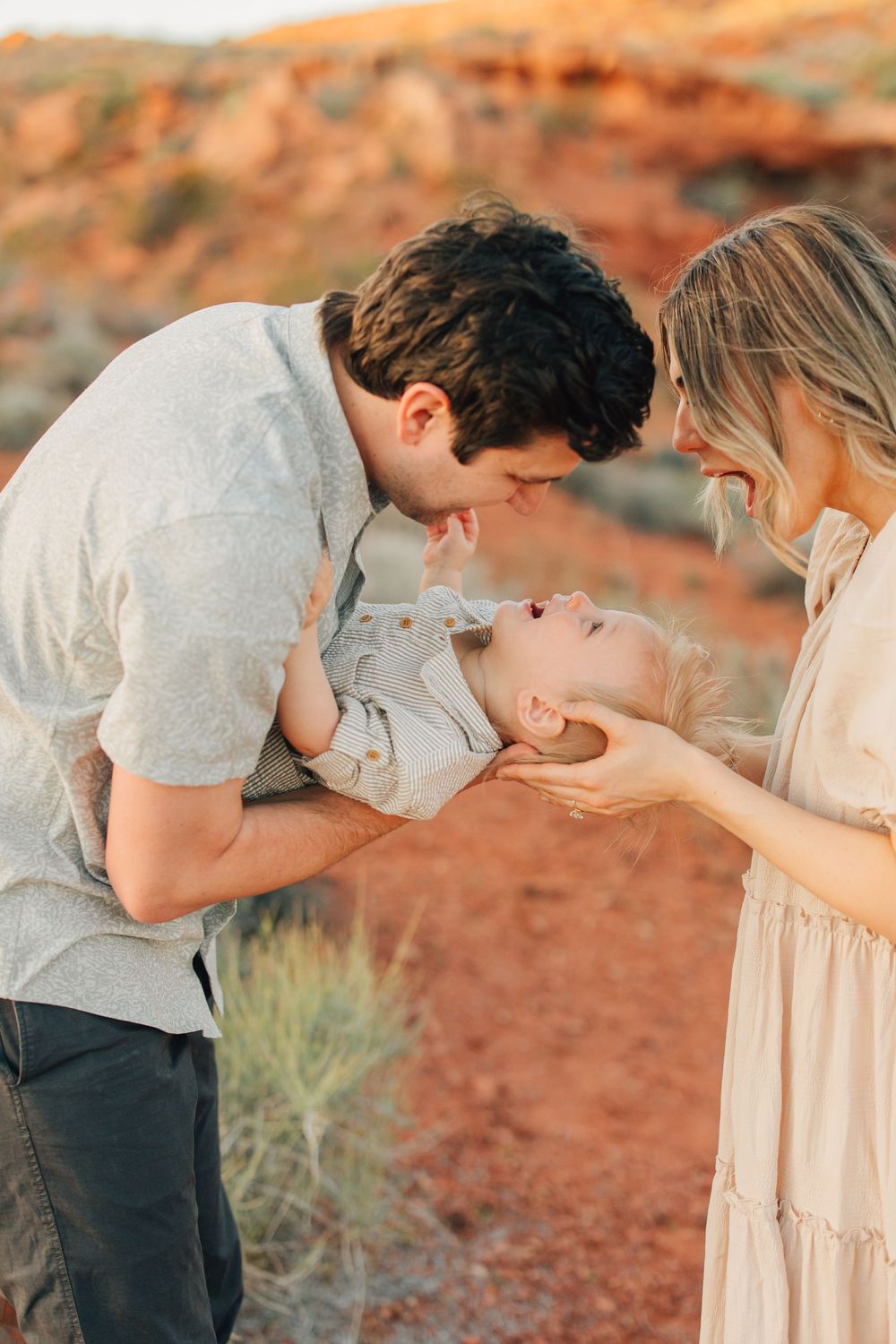 A couple lovingly holds their newborn baby in a stunning desert landscape.