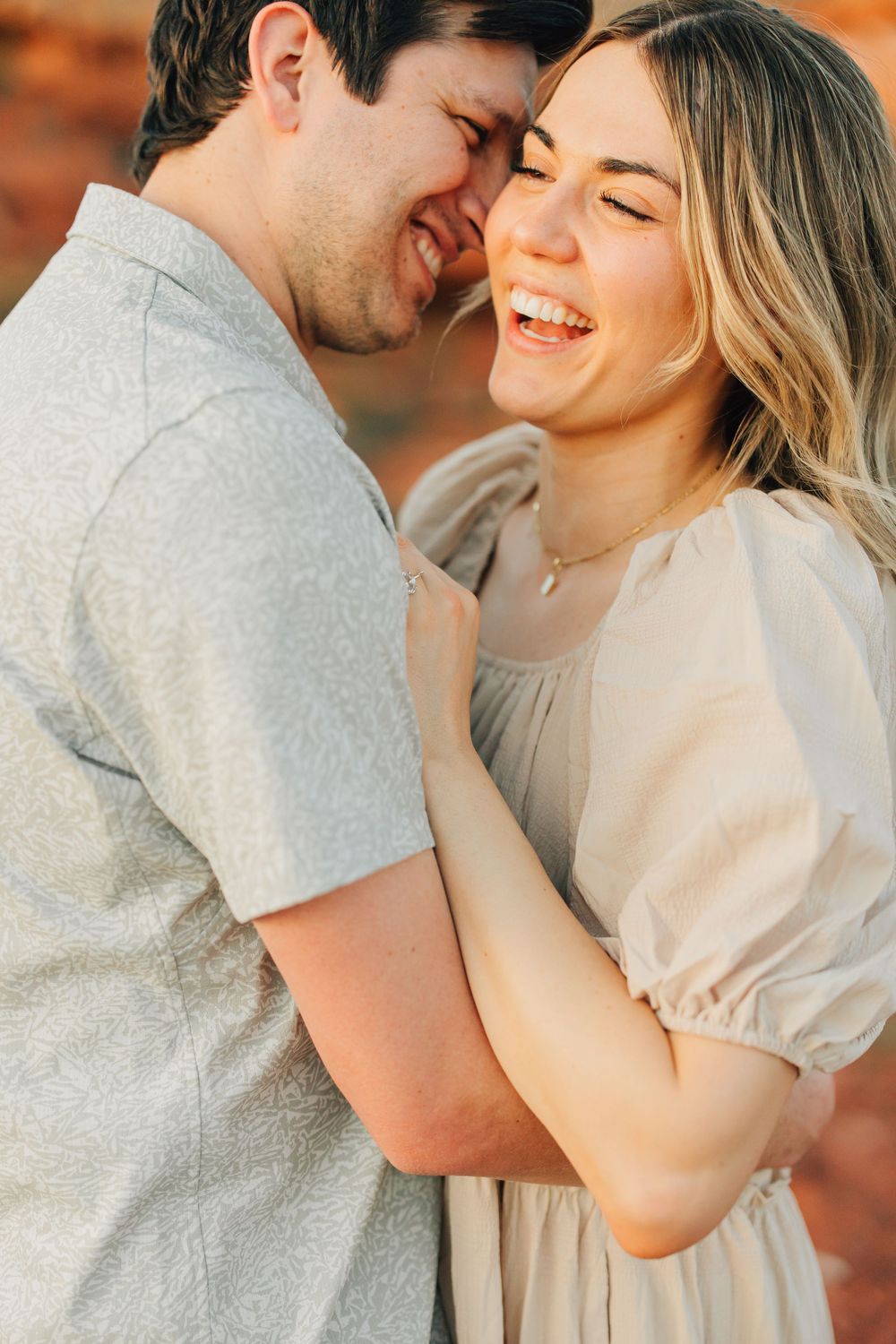 A couple embraces and smiles joyfully in a picturesque outdoor setting.