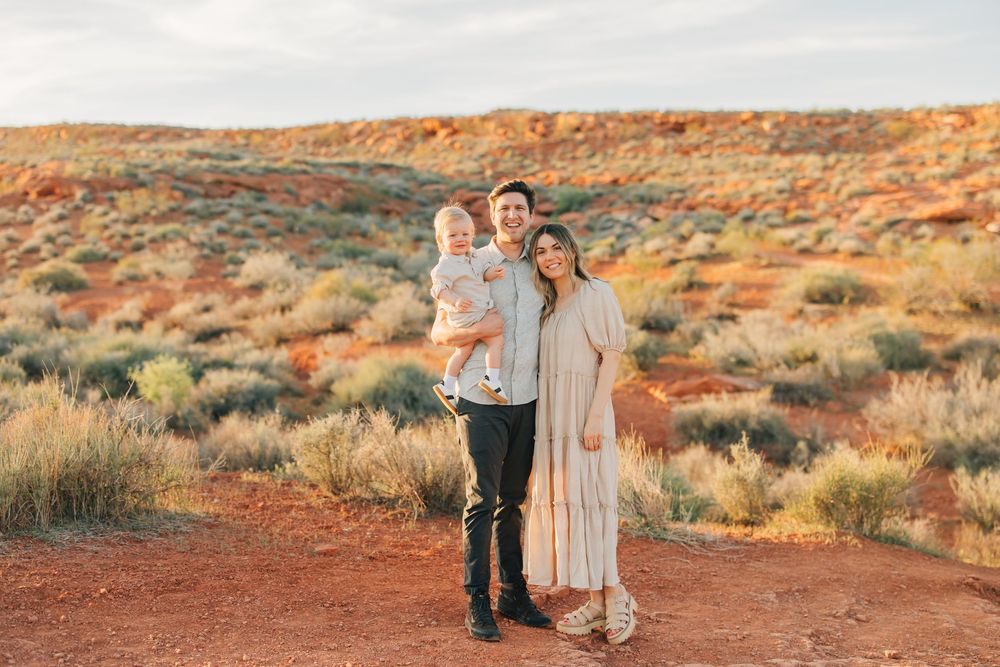 A family standing together in a scenic desert landscape with red rock formations in the background.