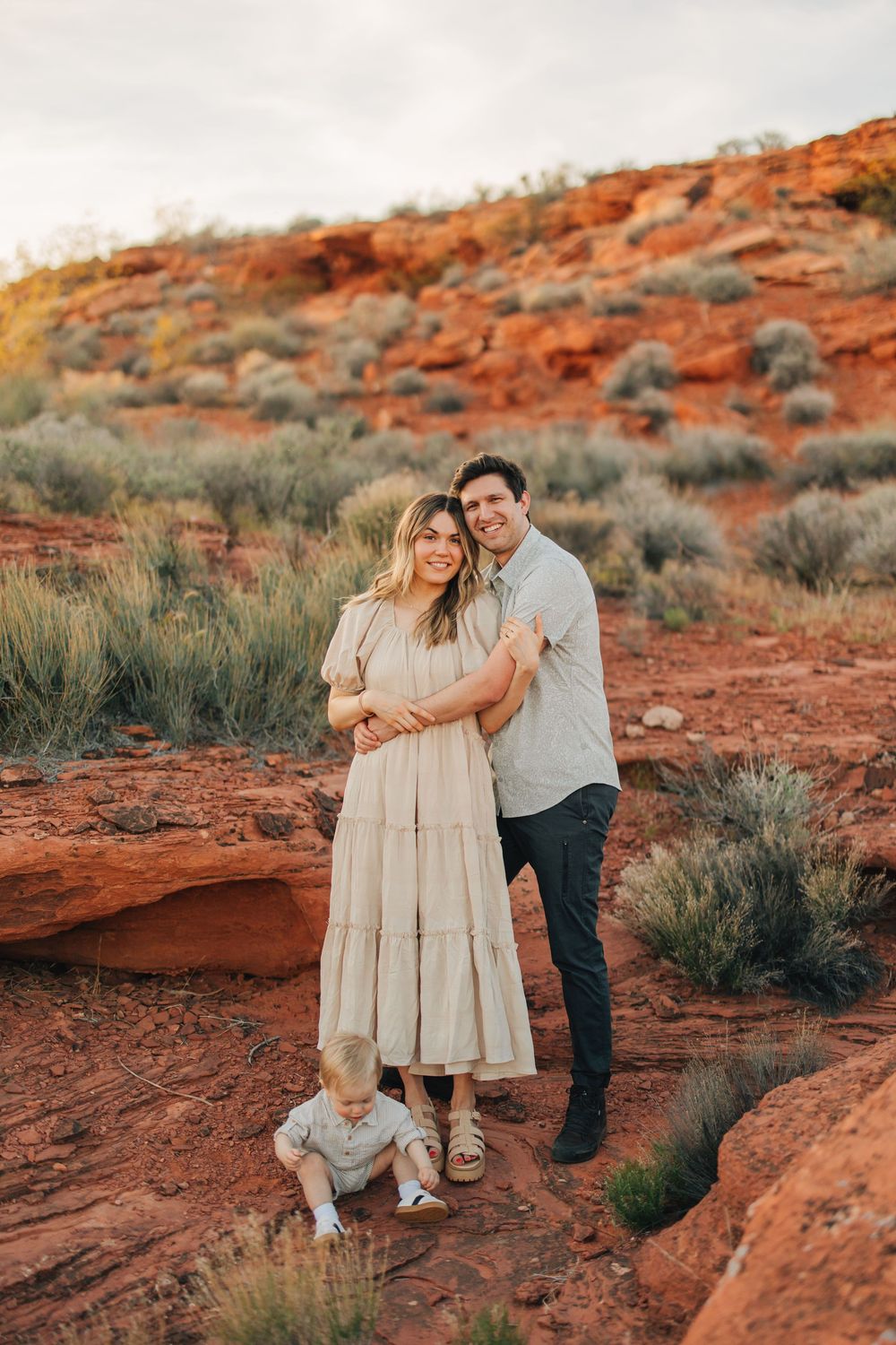 A couple embracing and posing for a photograph in a beautiful desert landscape.
