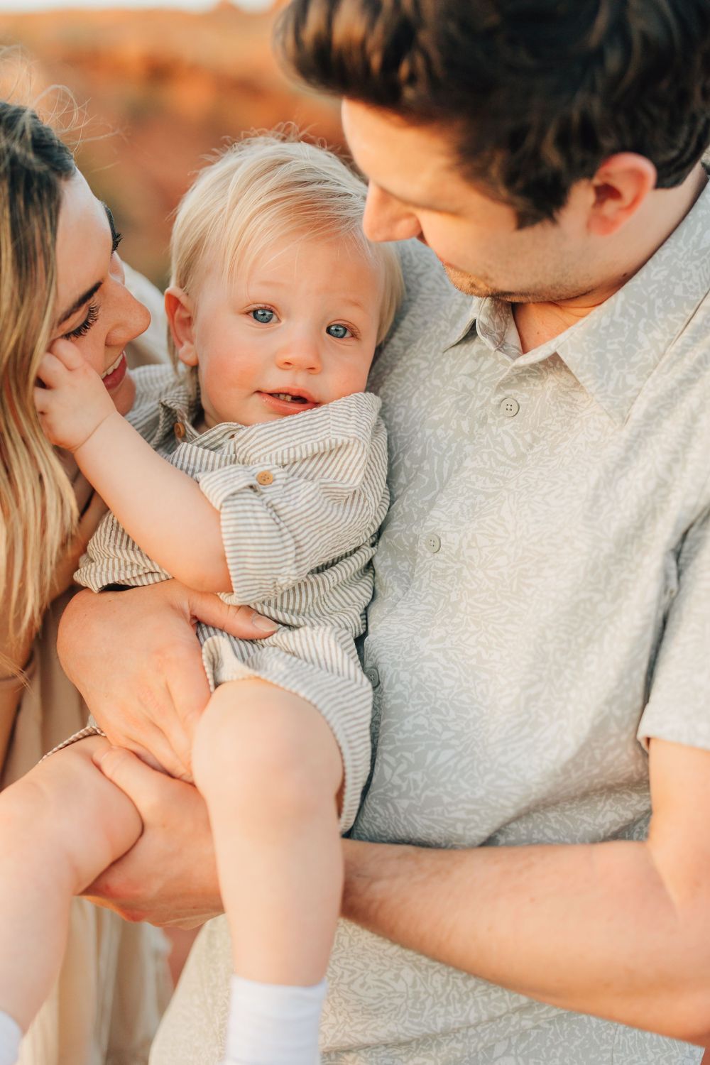 A couple cuddling and smiling at their adorable baby in a warm, loving moment.