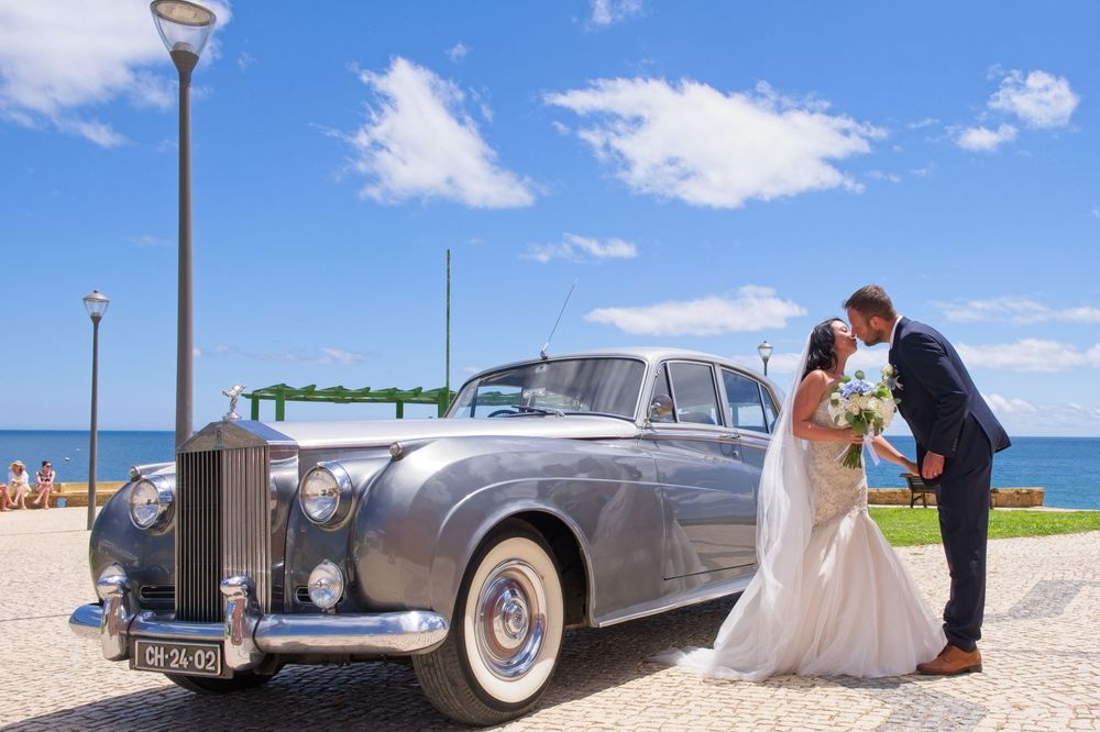 Next to a Rolls Royce, the newlyweds celebrate their wedding with a kiss.