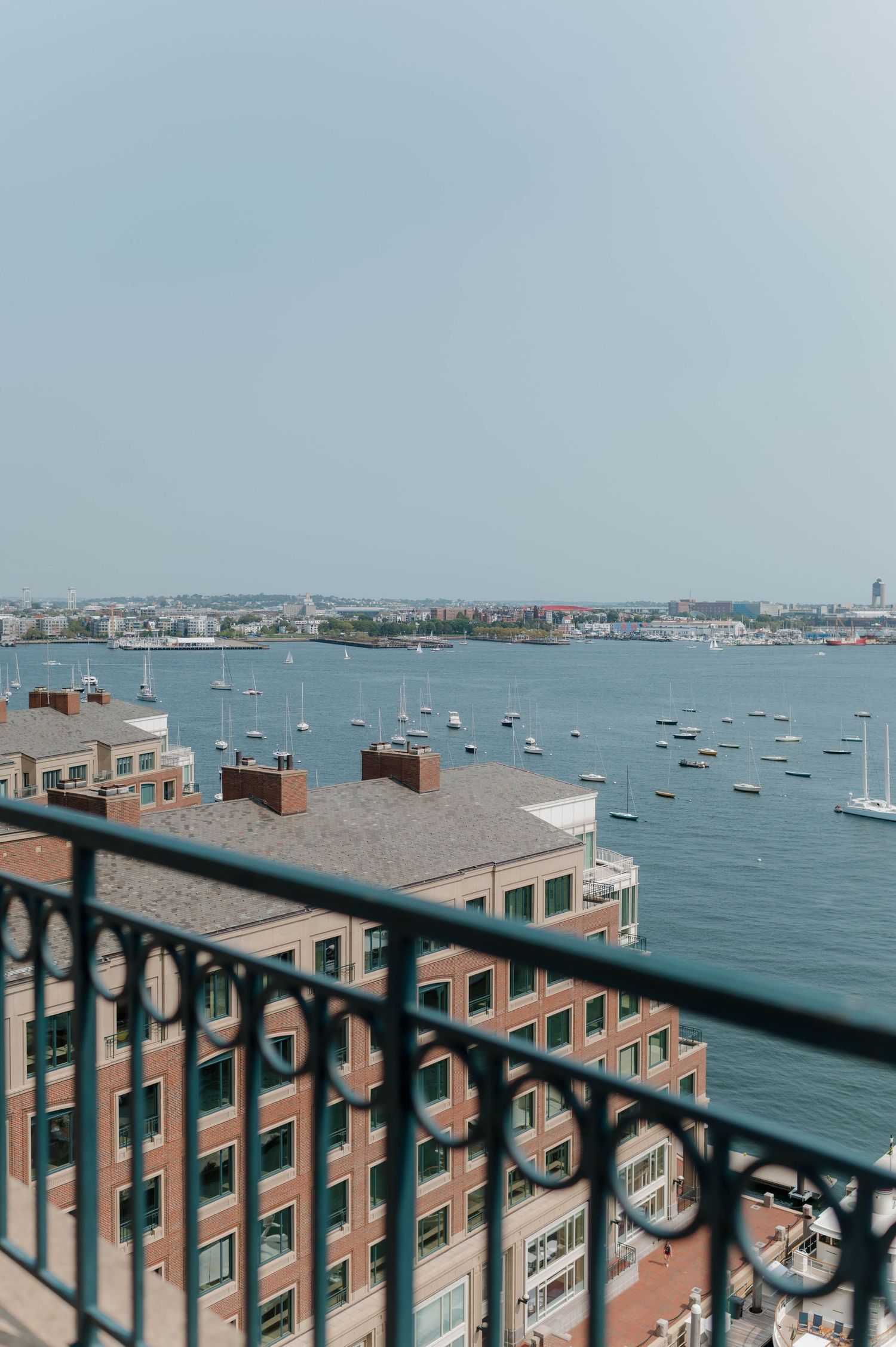 Panoramic view of Boston Harbor with boats anchored in the water and brick buildings along the waterfront.