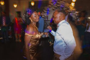 People dancing together at an evening celebration with warm amber and purple lighting effects.