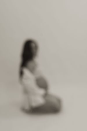 A blurred artistic maternity photo series showing movement and silhouettes against a light background.