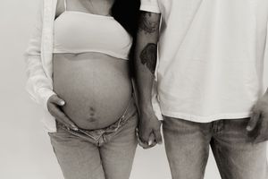 Black and white maternity photos showing intimate moments between couple in casual attire.