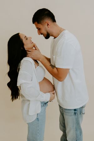 A couple in white tops and jeans share tender moments during an intimate photo session.