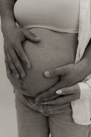Close-up black and white shots of hands cradling pregnant belly.