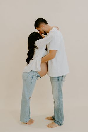 Intimate maternity poses with couple in matching casual outfits.