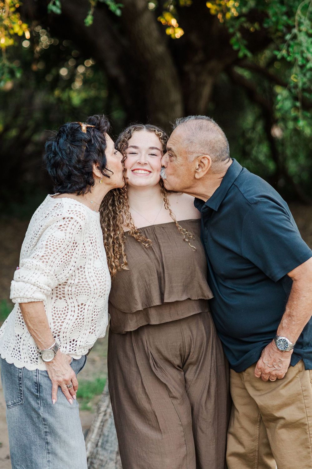 A sweet outdoor family portrait session showing three people sharing affectionate moments in a natural setting.