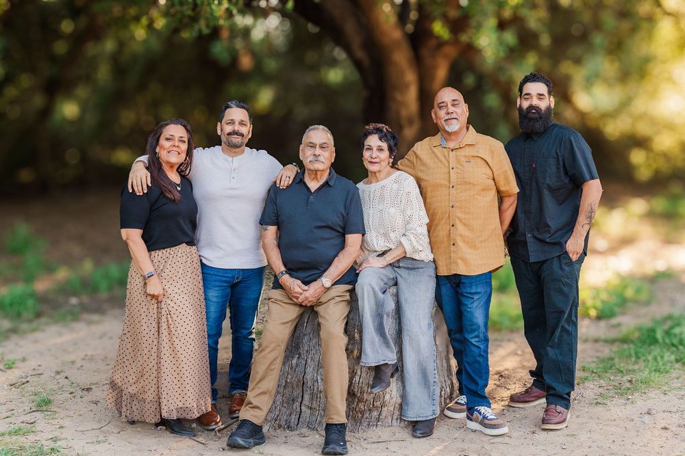 A group wearing coordinated casual outfits in earth tones poses together outdoors during golden hour lighting.