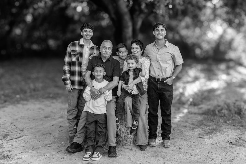 A black and white photo series shows a family sitting together outdoors for professional portraits.