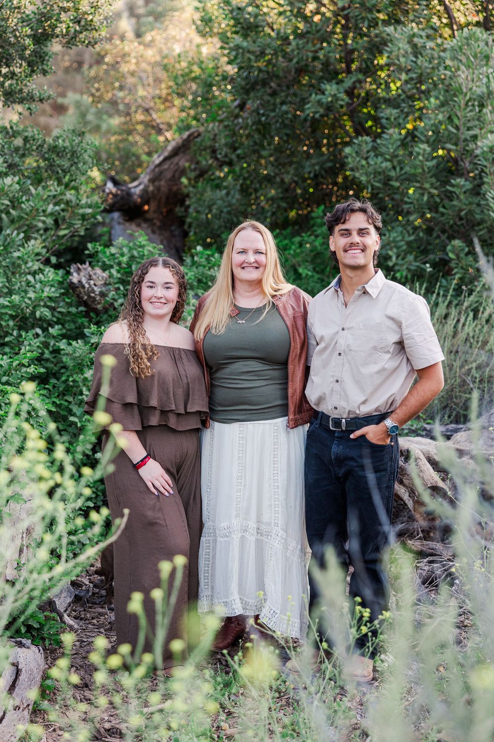 Group photo taken outdoors in a natural setting with greenery and foliage in the background.