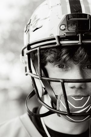 Close-up black and white portrait showing partial view of football helmet and facemask.