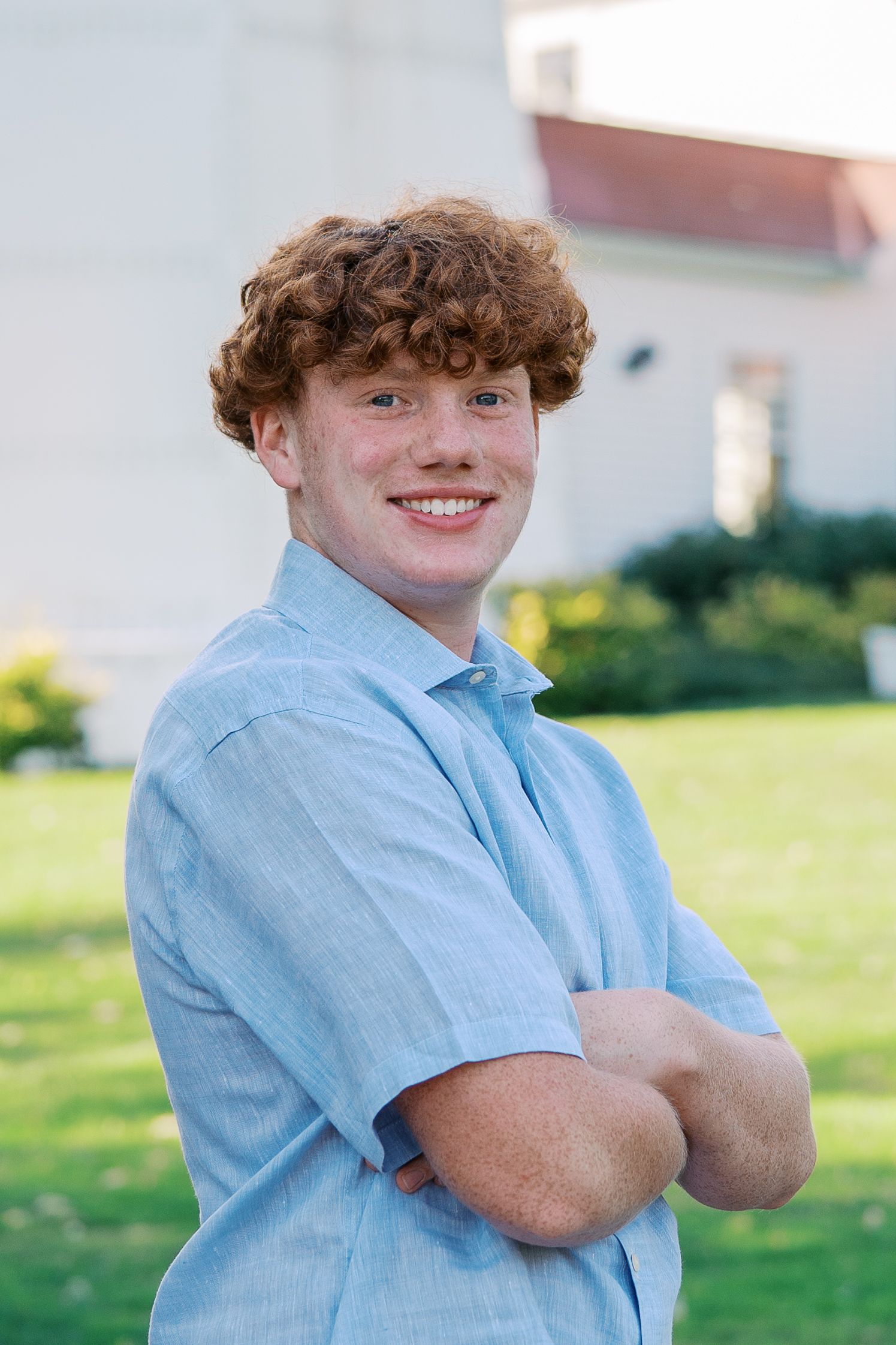 Portrait of someone in blue shirt standing outdoors on sunny day.