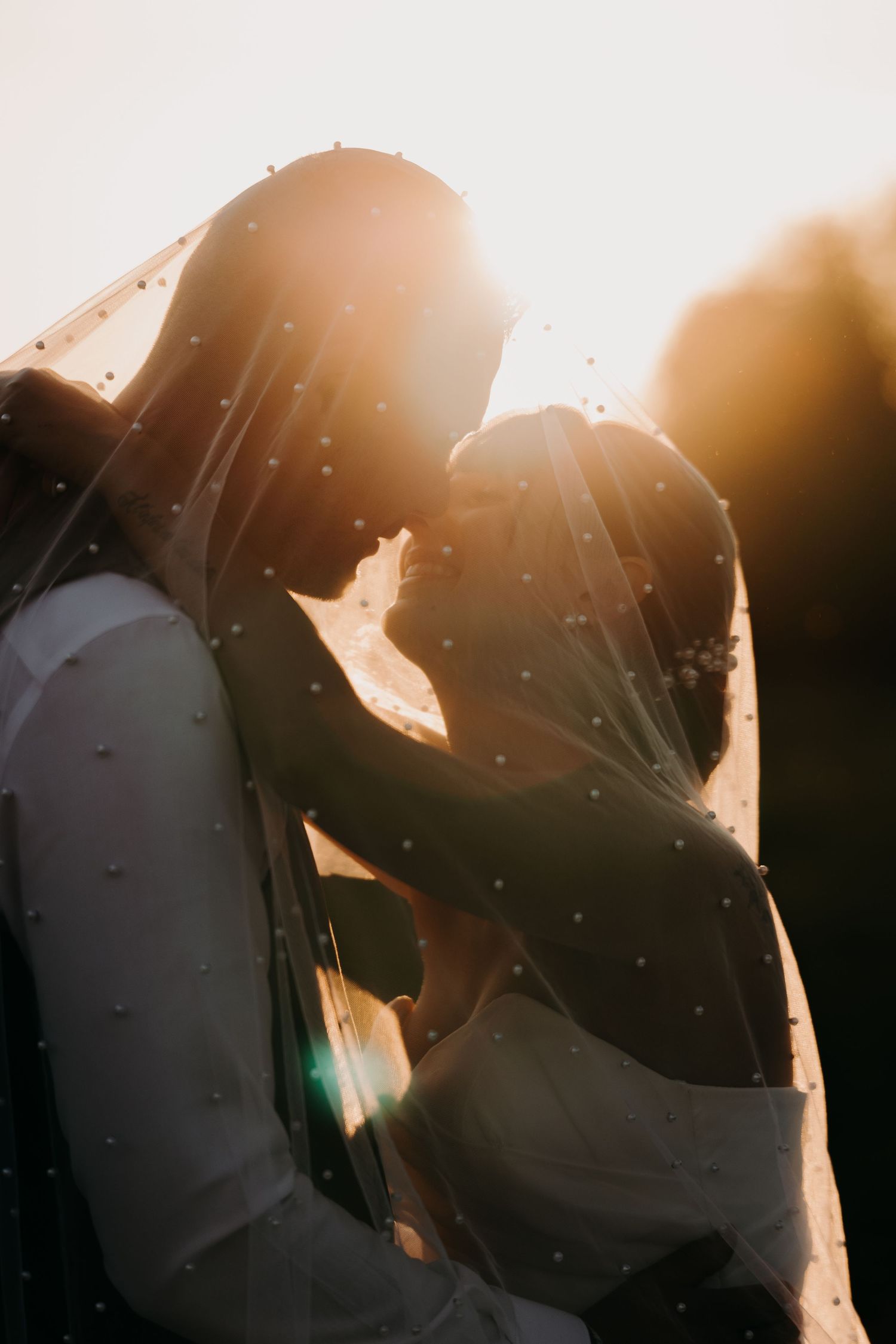Silhouetted couple sharing intimate moment in sunset backlight.