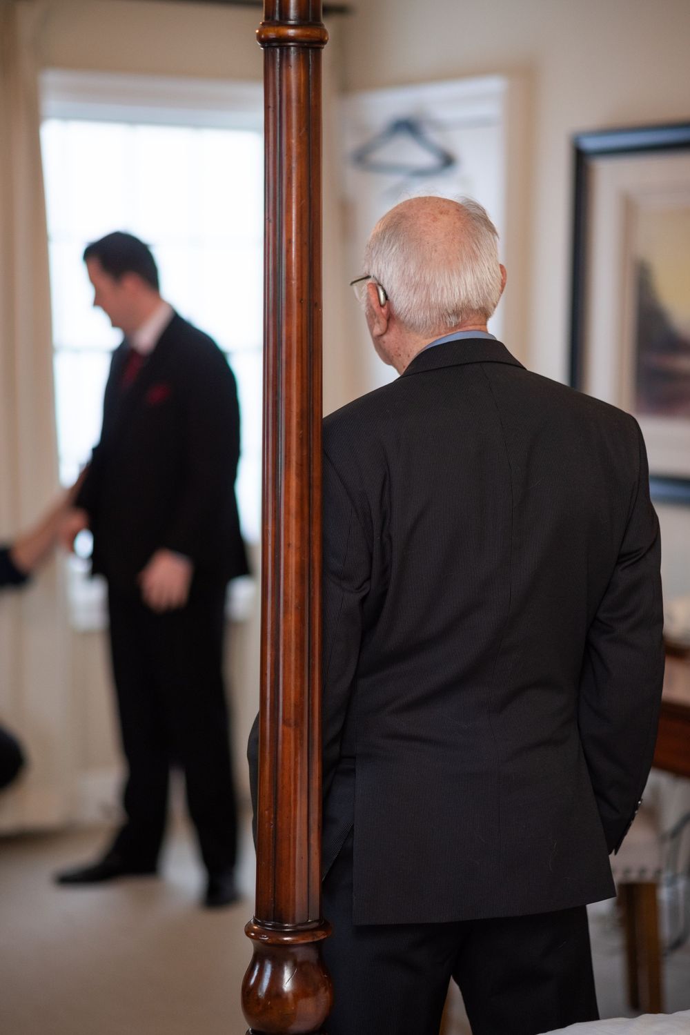 Multiple people in dark suits stand in a hallway, shown in a blurred sequence of candid moments.