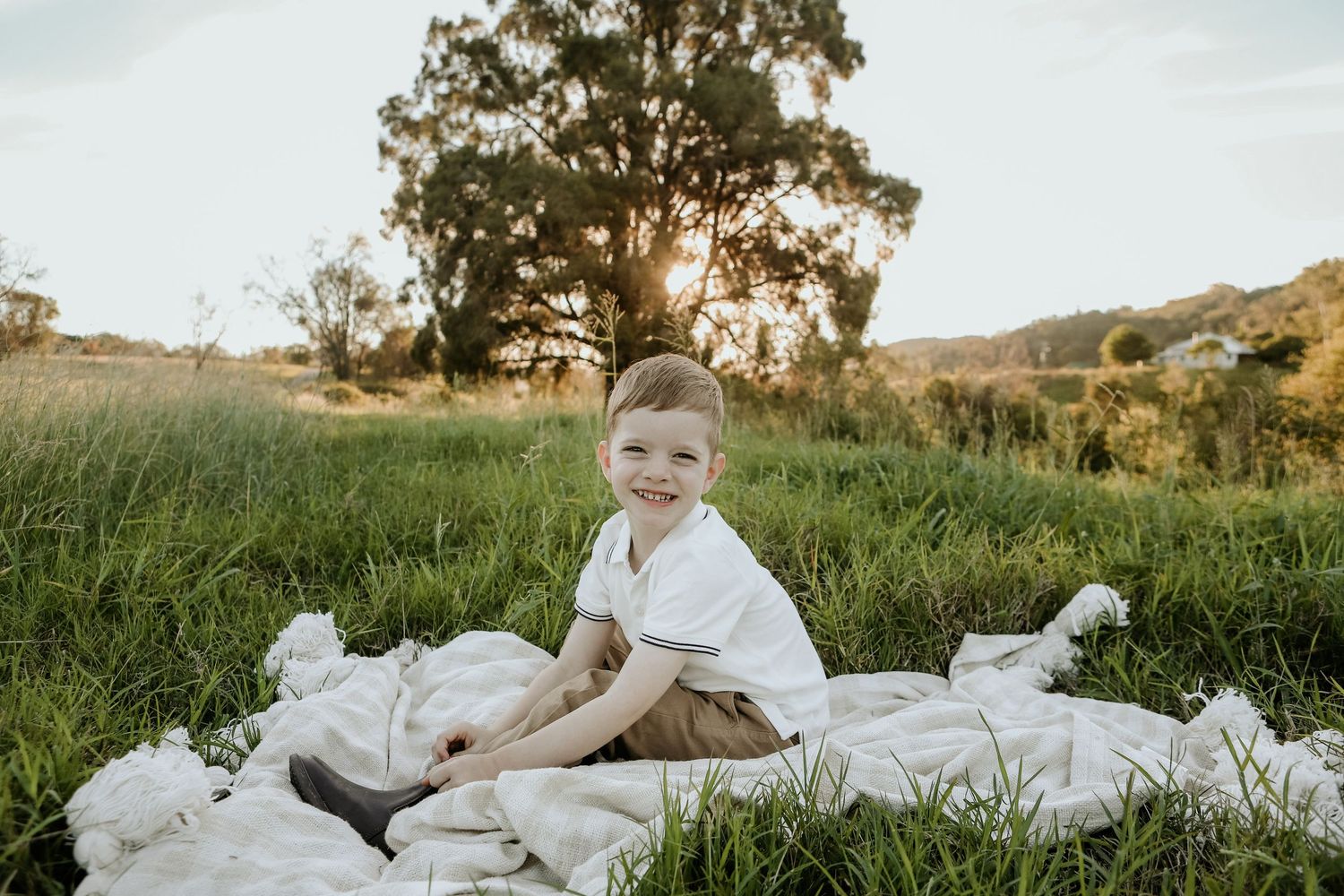A series of outdoor family portraits on a white blanket in a grassy field at golden hour.