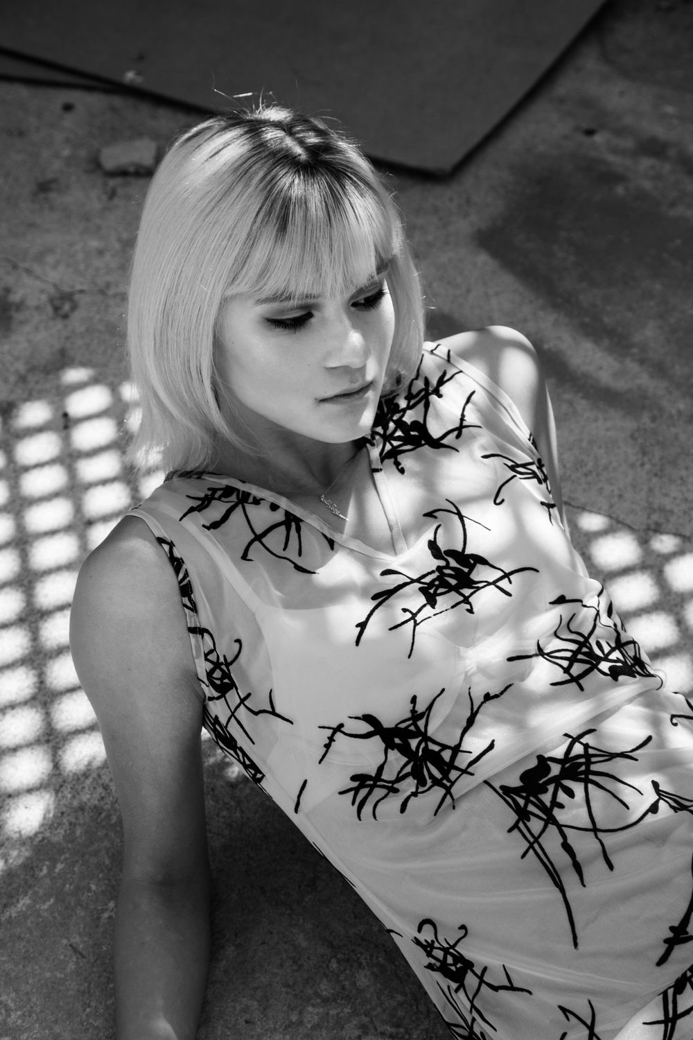 Black and white portrait showing dappled light and shadow patterns across the frame.