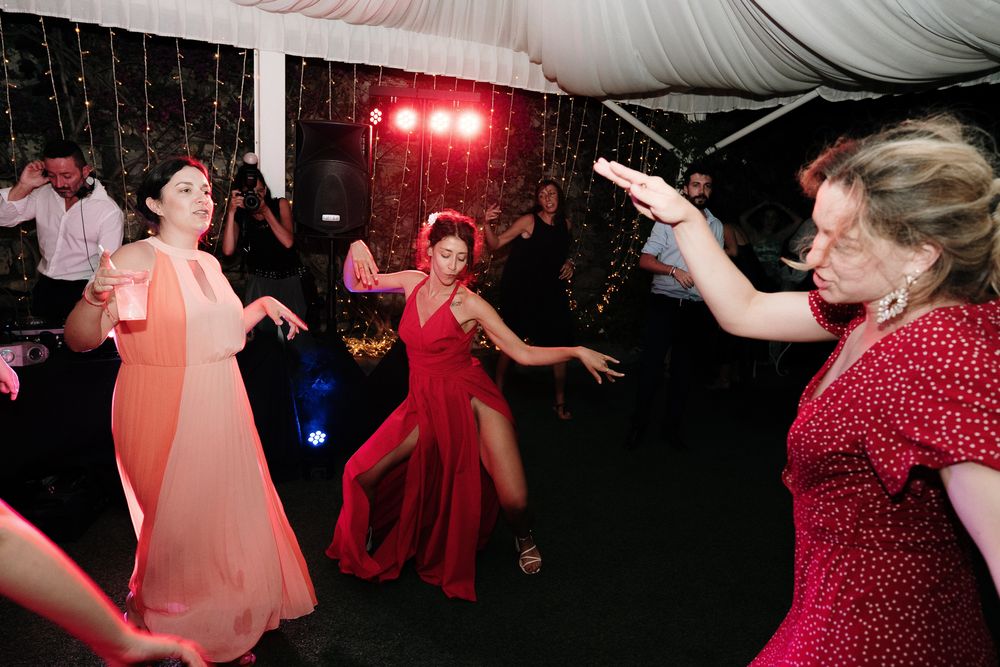 Guests dancing during the wedding evening party at Villa Casa Rossa in Imperia with red lights and a festive atmosphere.