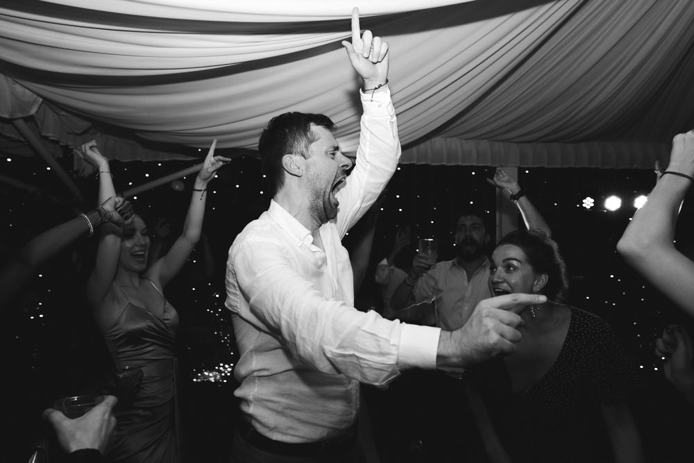 Guests singing and dancing under the illuminated marquee during the wedding party in Imperia.