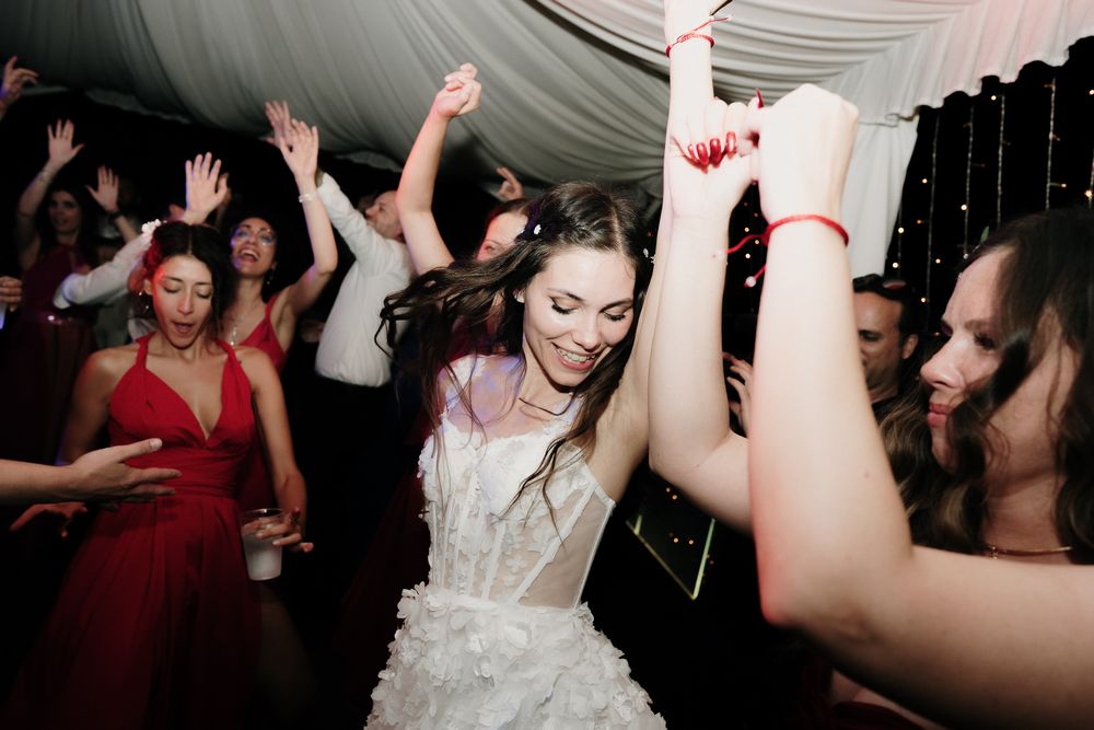 Bride dancing with arms raised during wedding disco at Villa Casa Rossa