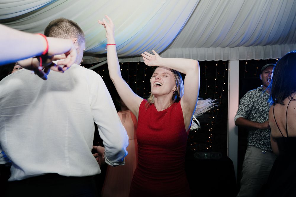 A guest in a red dress dances enthusiastically during the wedding party in Imperia.