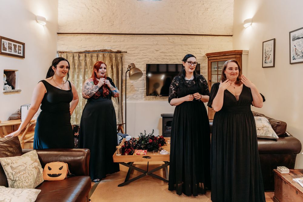 People in black dresses dance and celebrate together in a bright indoor space during a special occasion.