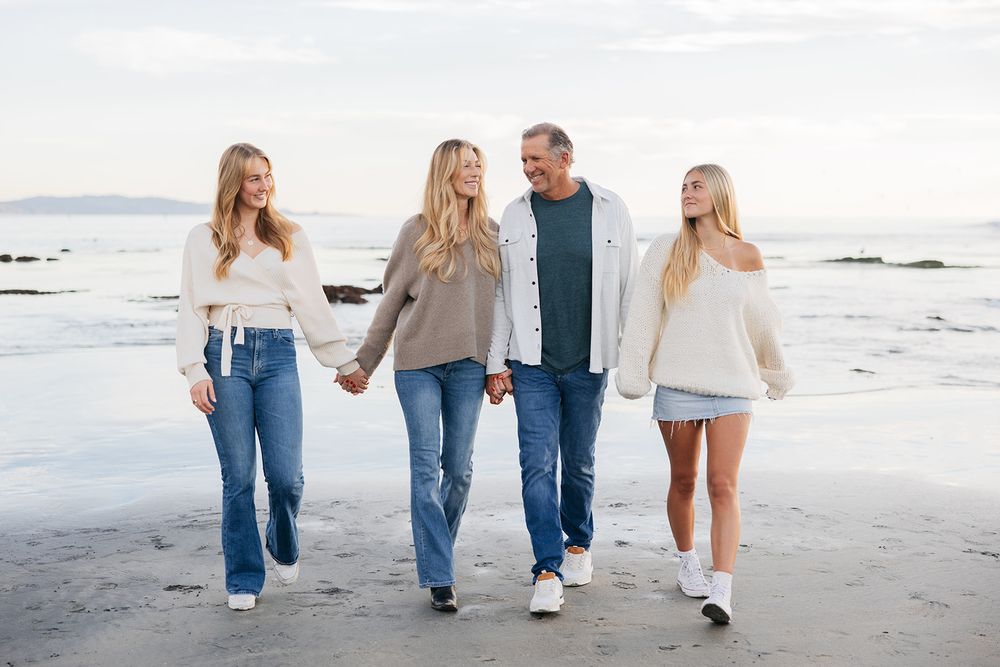 Group walking together on a beach at sunset wearing casual clothing and denim.