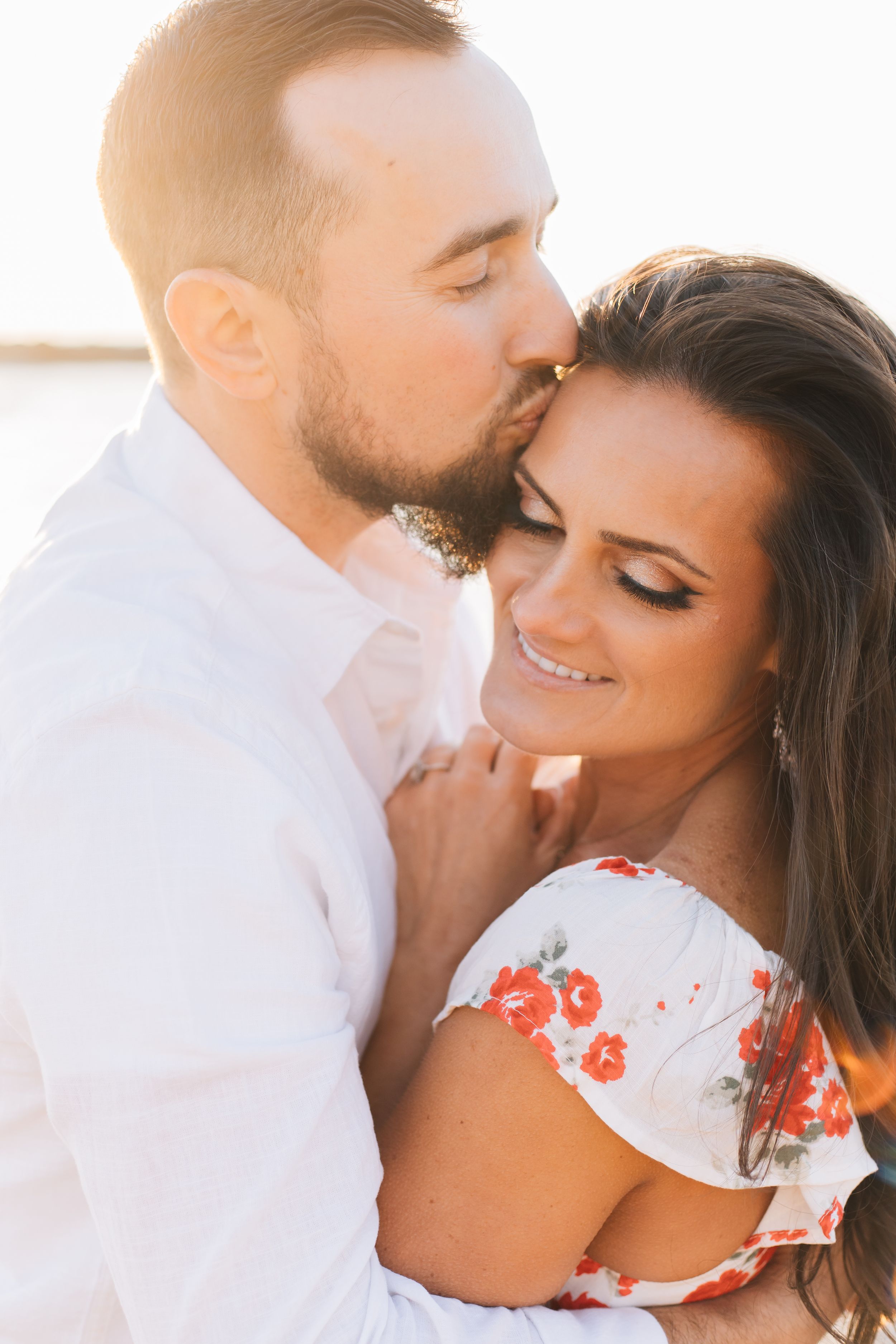 An intimate moment between a couple during a sunset photoshoot.