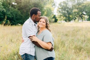 Affectionate couple embracing in sunny meadow with tall grass.