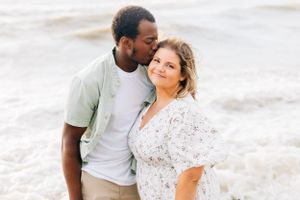 Romantic couple sharing a tender moment on the beach at sunset.