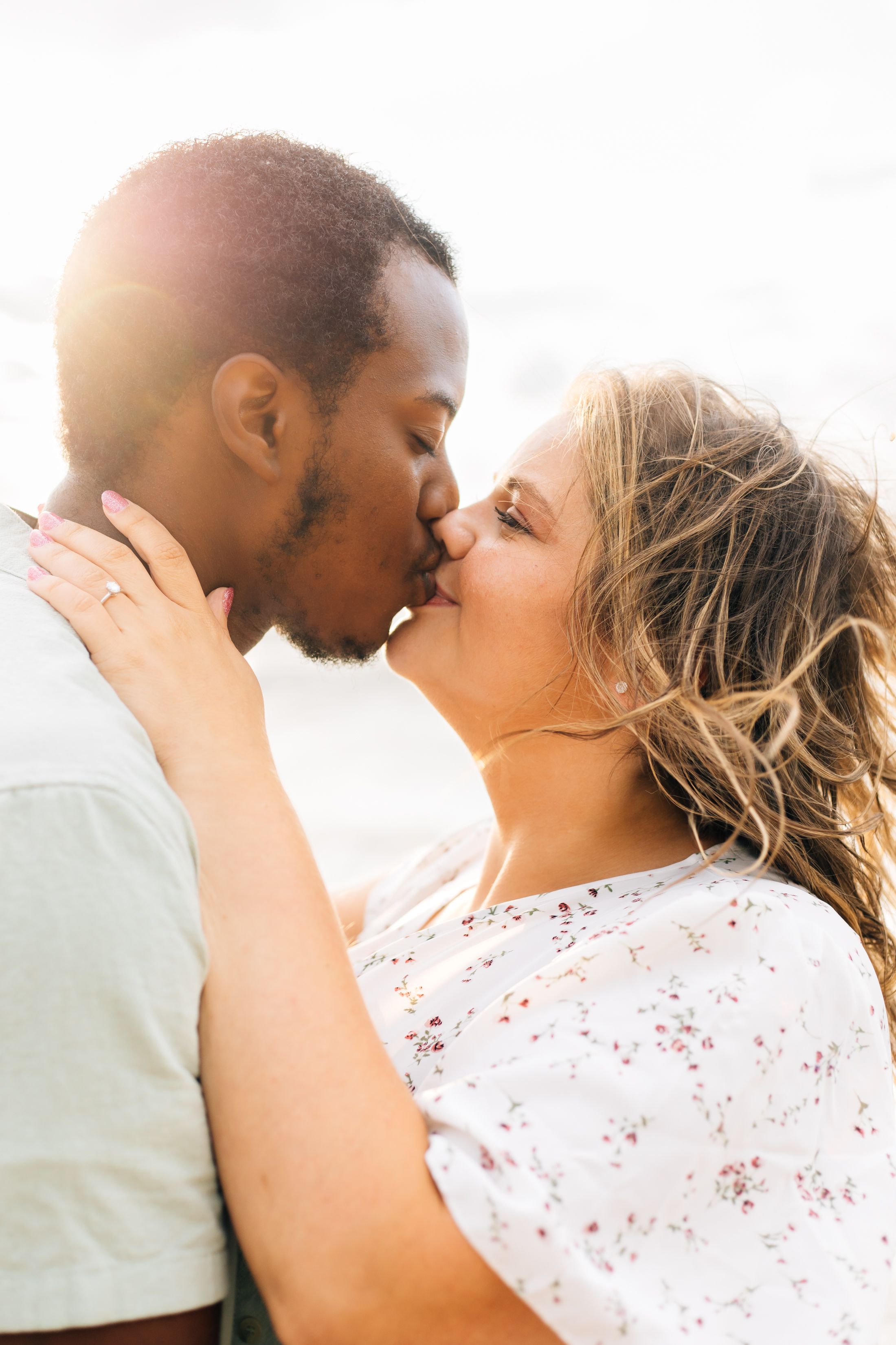 A tender romantic moment between a couple sharing a kiss in warm sunlight.