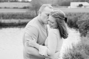Intimate black and white portrait of a couple embracing by a lake.