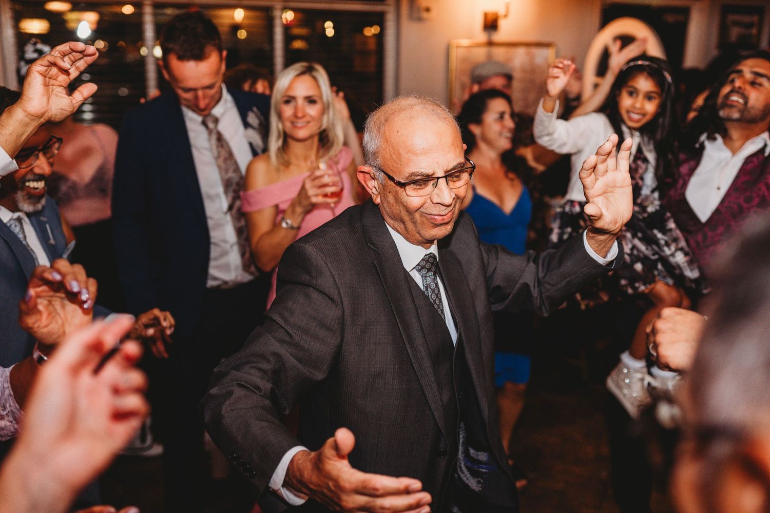 Guests dancing and celebrating at indoor wedding reception.