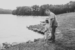 Black and white photo of figures fishing by a serene lakeside.