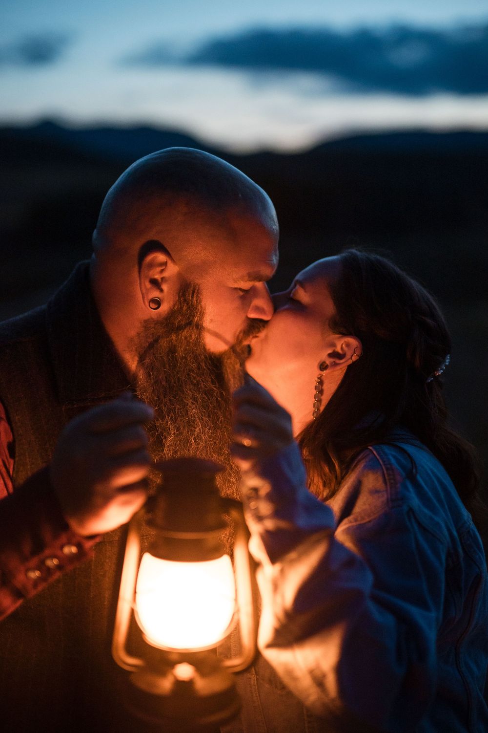 A romantic couple shares an intimate moment in the warm glow of an antique lantern at dusk.