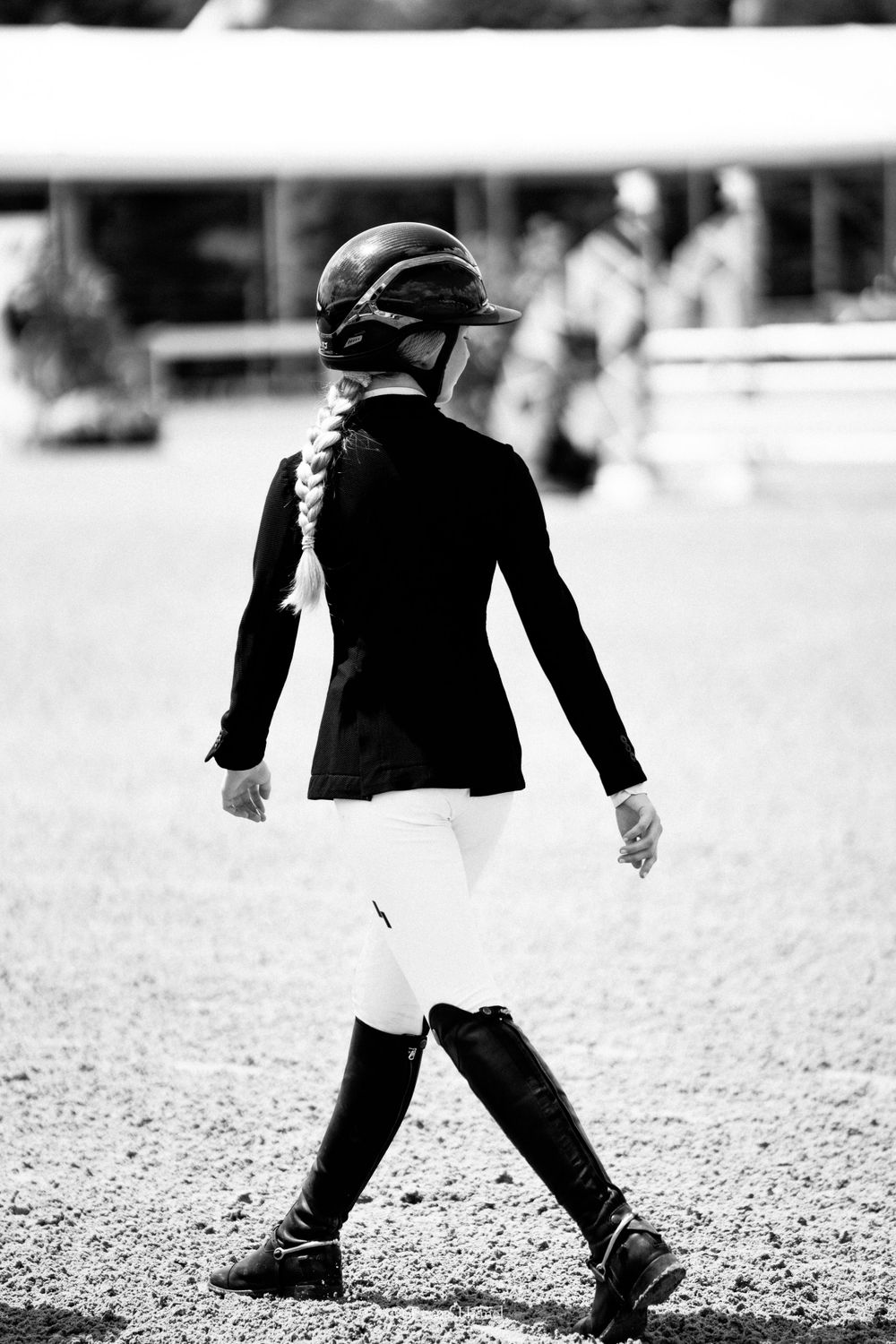 Equestrian rider in formal show attire walking in competition arena.