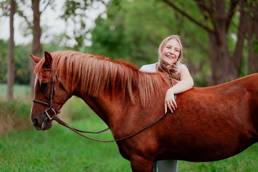 Beautiful chestnut horse with flowing mane and girl outdoors.