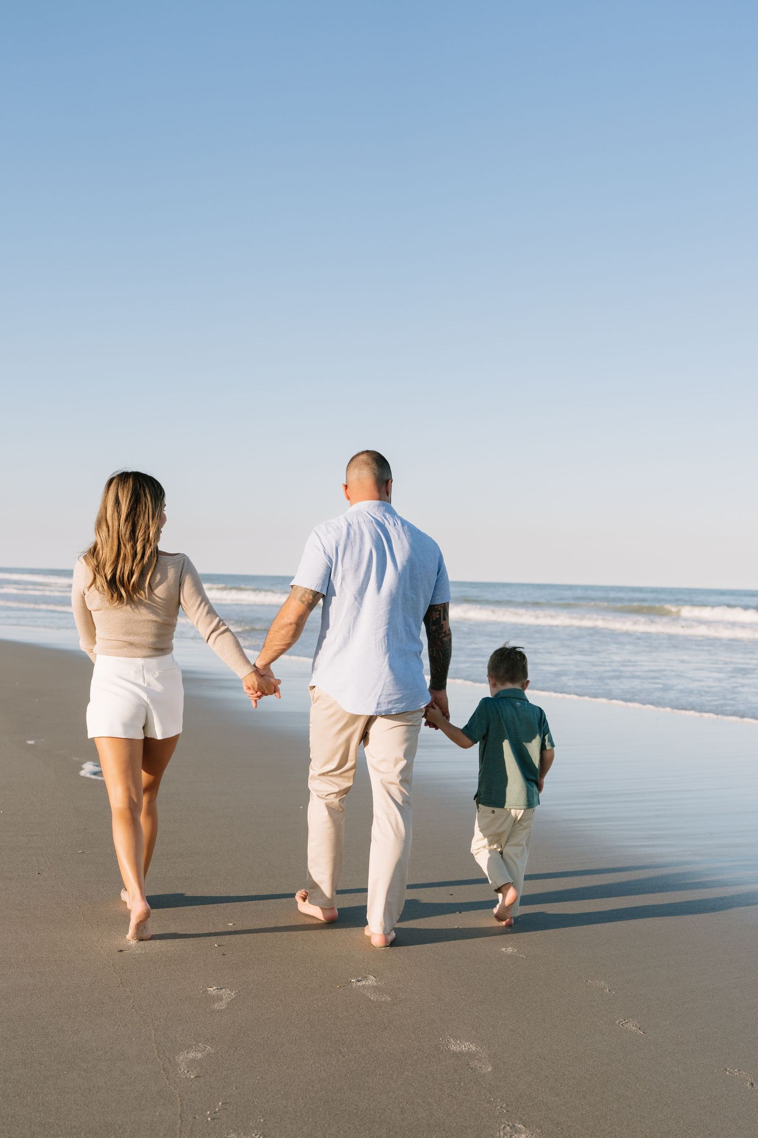 A group walks together along a sandy beach path under cloudy skies.