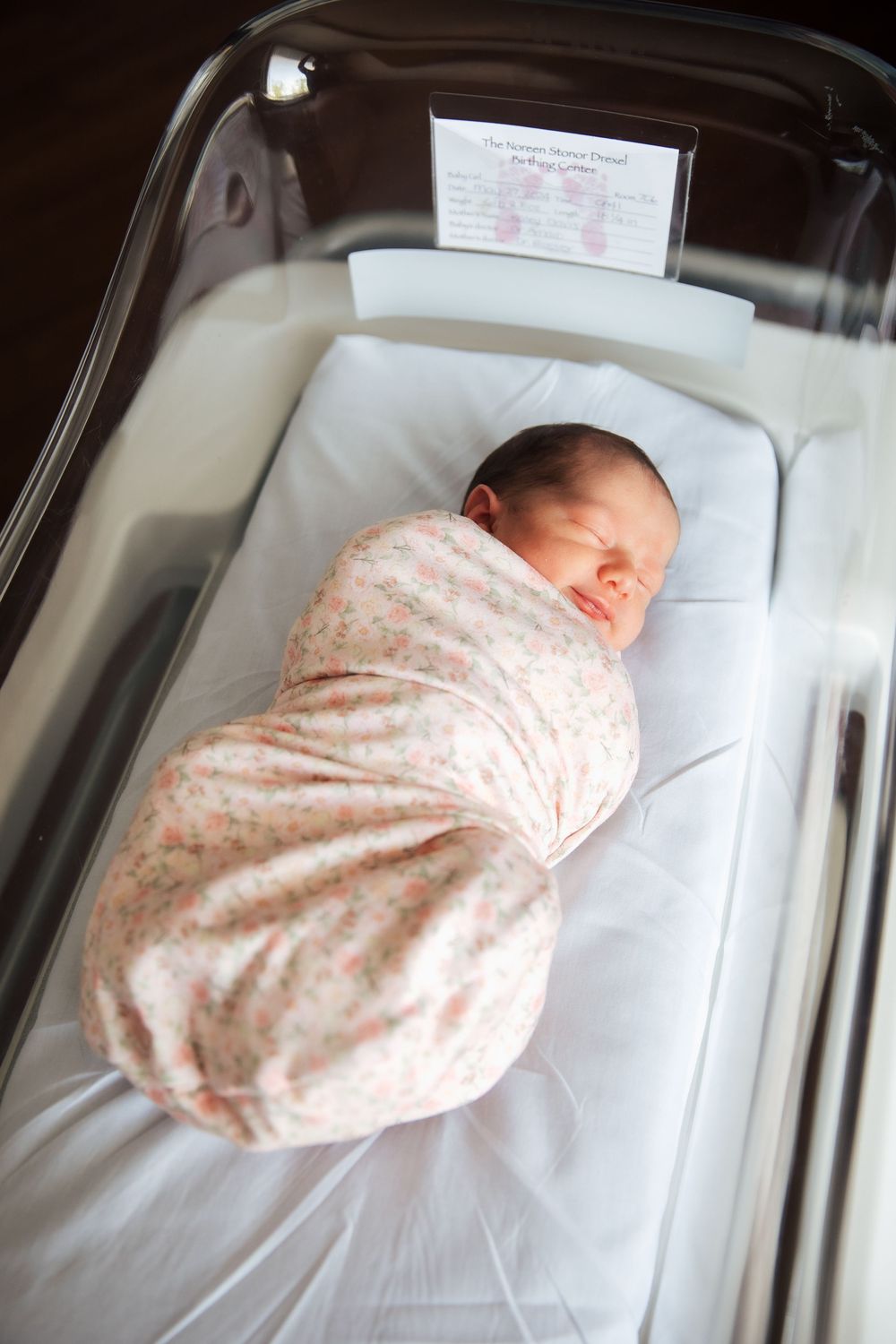 Newborn baby swaddled in floral blanket sleeping peacefully in hospital bassinet after birth. fresh 48, Newport Hospital