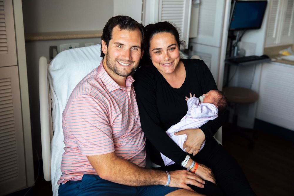 Happy couple smiling in hospital room holding their newborn baby wrapped in white blanket. fresh 48, Newport Hospital