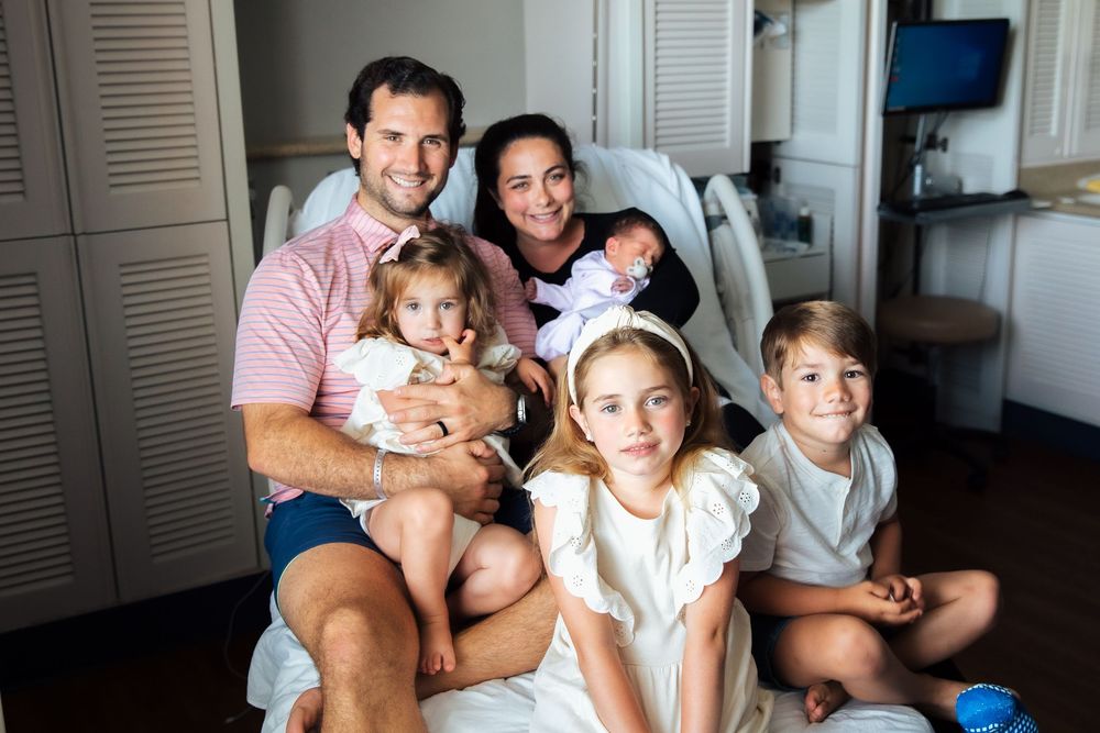 Happy family of six poses together in a hospital room celebrating the arrival of their newborn baby. fresh 48, Newport Hospital