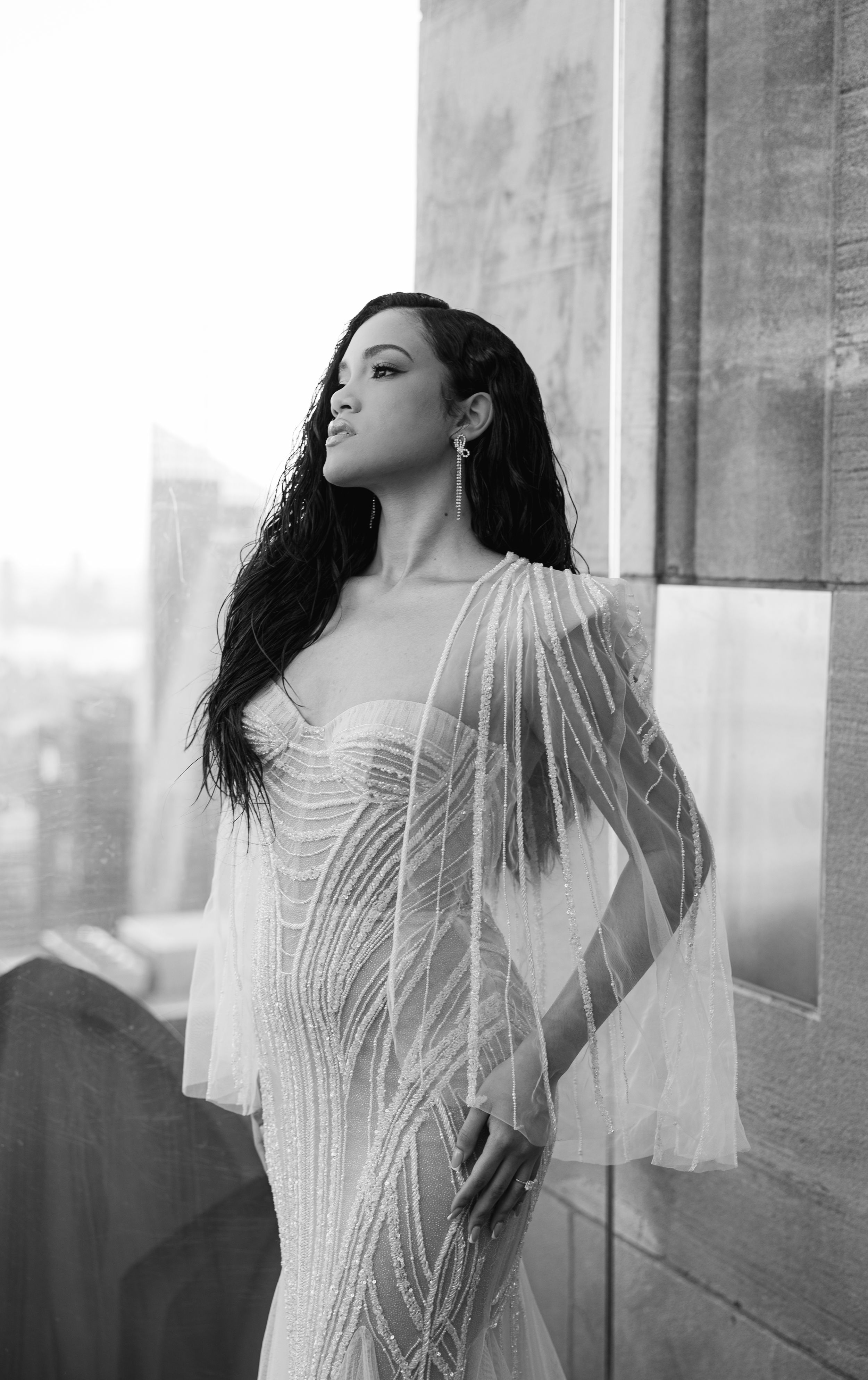 Black and white portrait showing intricate beaded wedding dress with sheer sleeves.