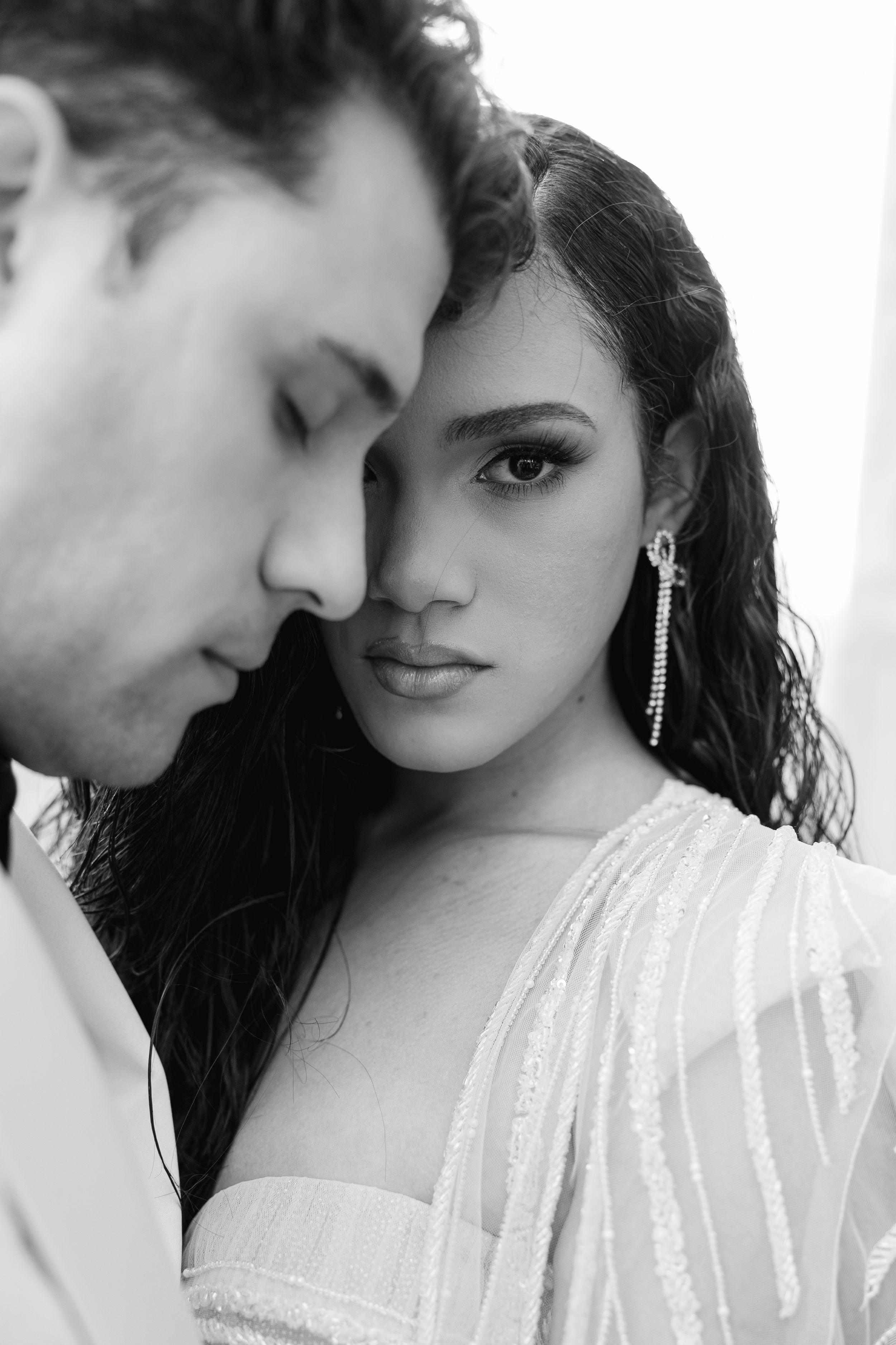 Close-up black and white portrait of couple in romantic pose wearing formal attire.