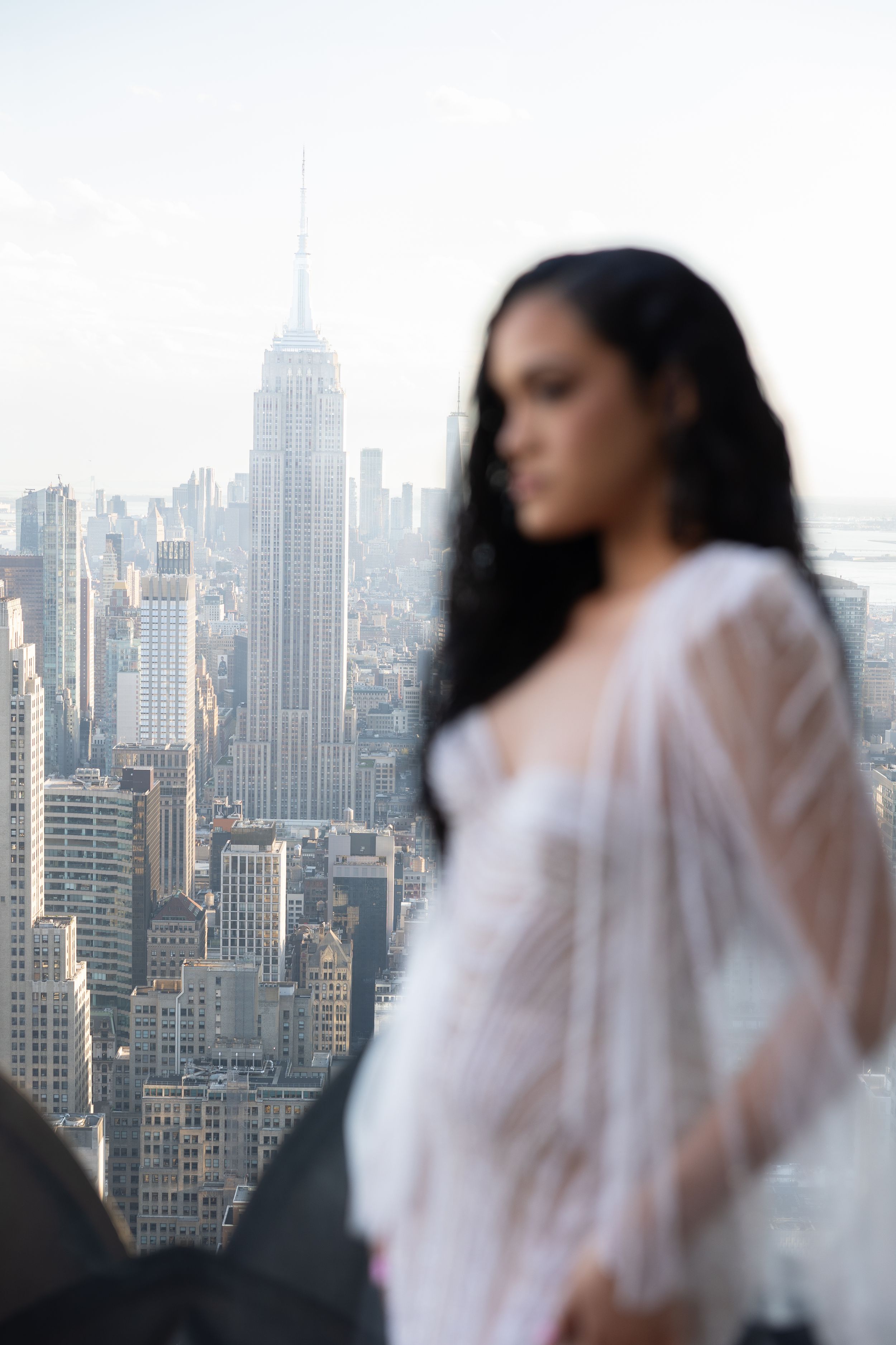Dreamy portrait with Empire State Building visible in background through city haze.