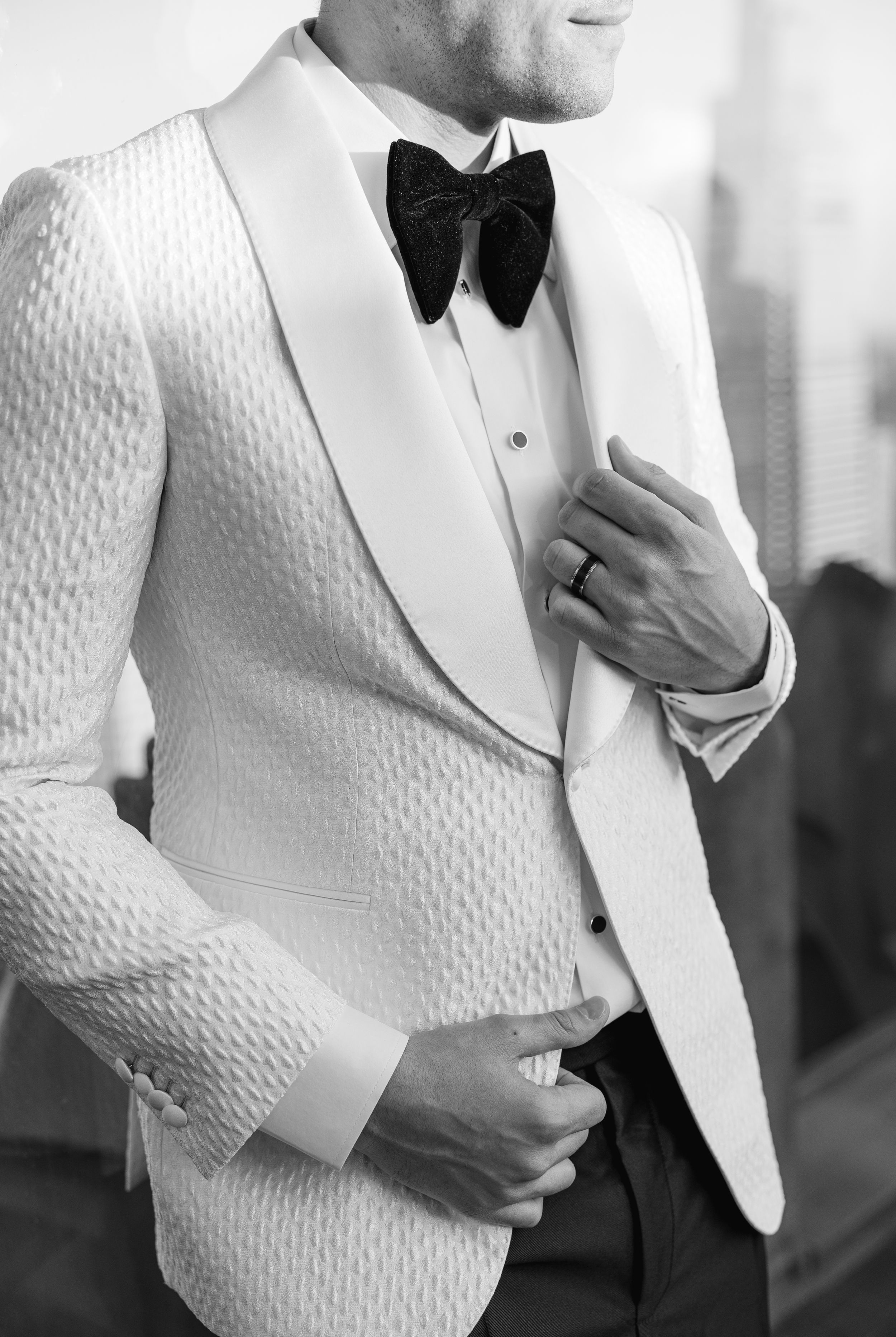 Elegant white textured tuxedo jacket with black bow tie detail shown in black and white.