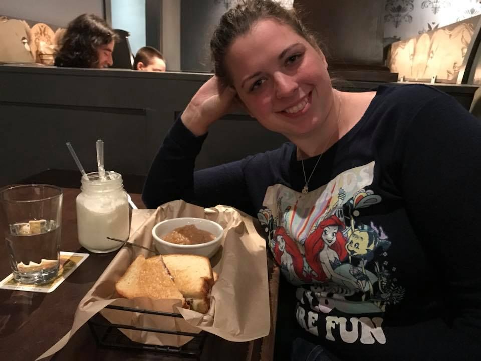 Diner seated at casual restaurant with food and milkshake on wooden table.
