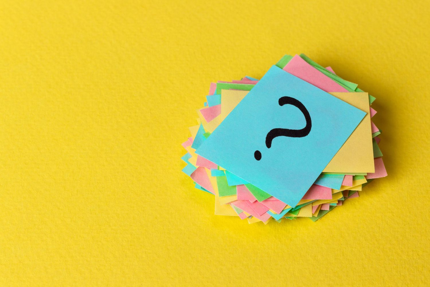 Question mark paper heap on yellow background, concept for confusion